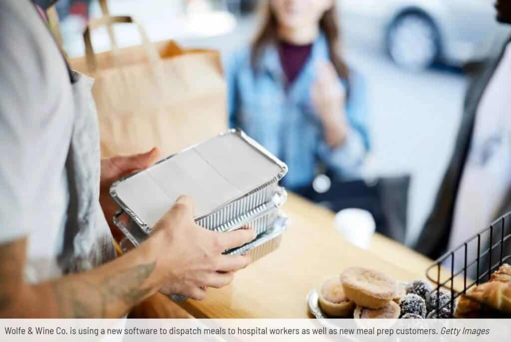 A caterer handing over stacked takeout food containers at a food counter with pastries displayed in the foreground uses Dispatch Science.