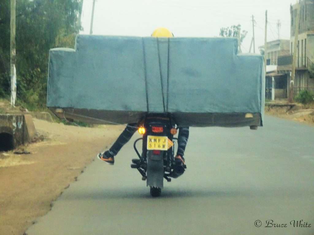 Motorcyclist transporting an oversized load on a road, coordinated through flexible dispatch management.